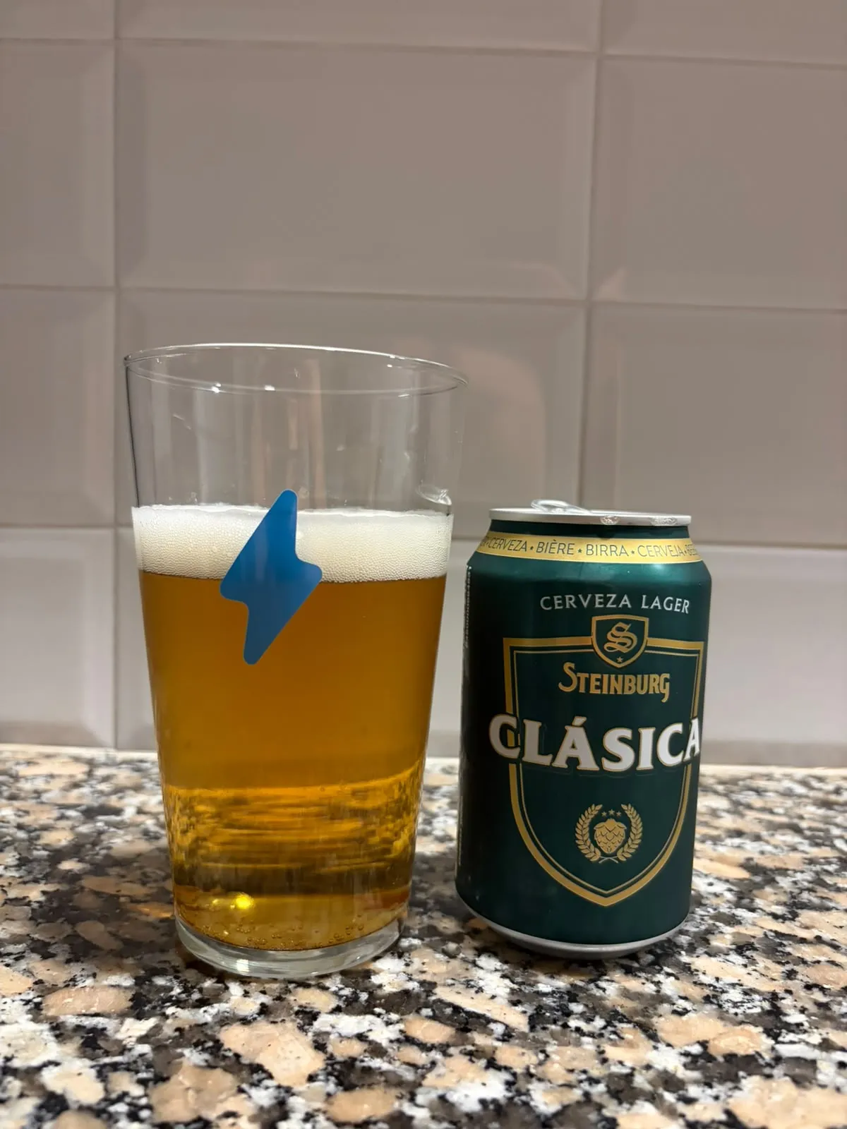 Steinburg Clásica servida en vaso: dorado pálido, limpia y con espuma blanca, junto a la lata